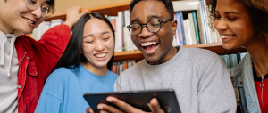 Grupo de estudantes observando algo no tablet e rindo