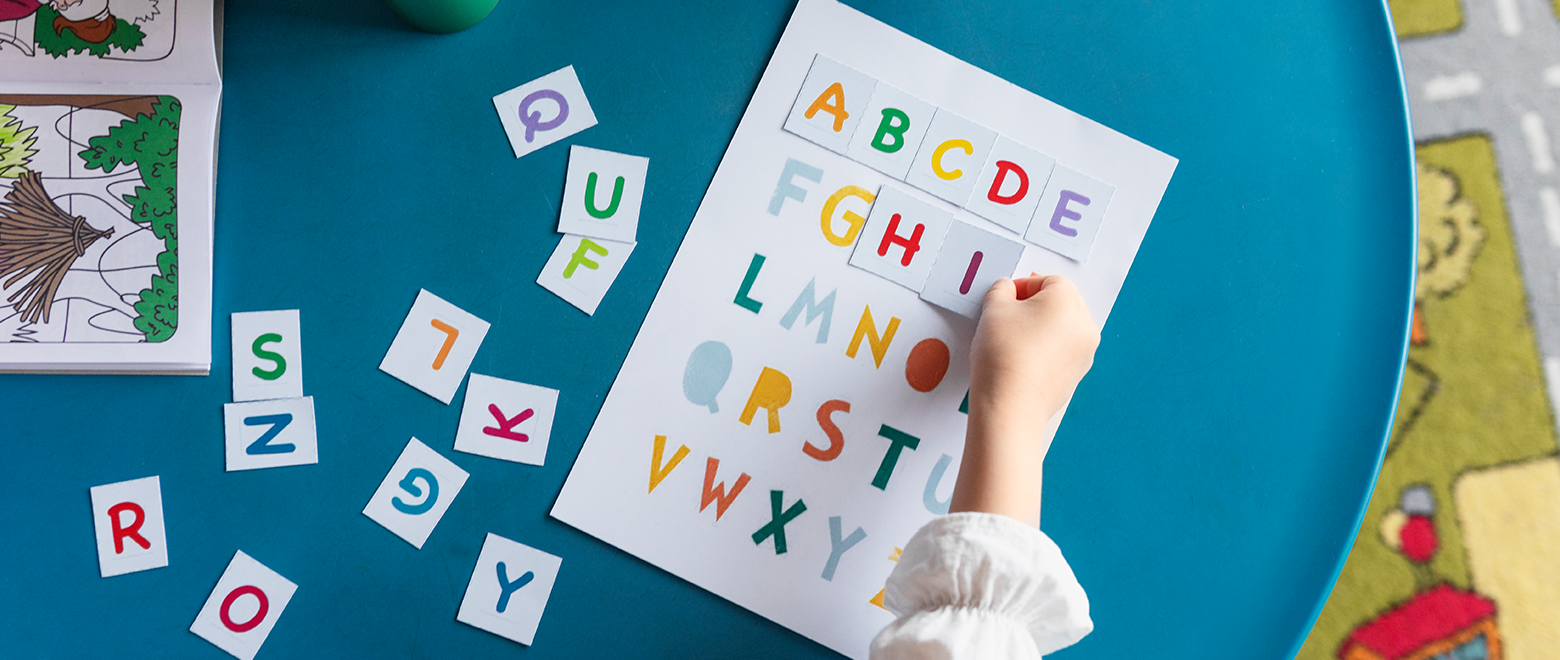 Visão de cima de crianças montando o alfabeto nas folhas