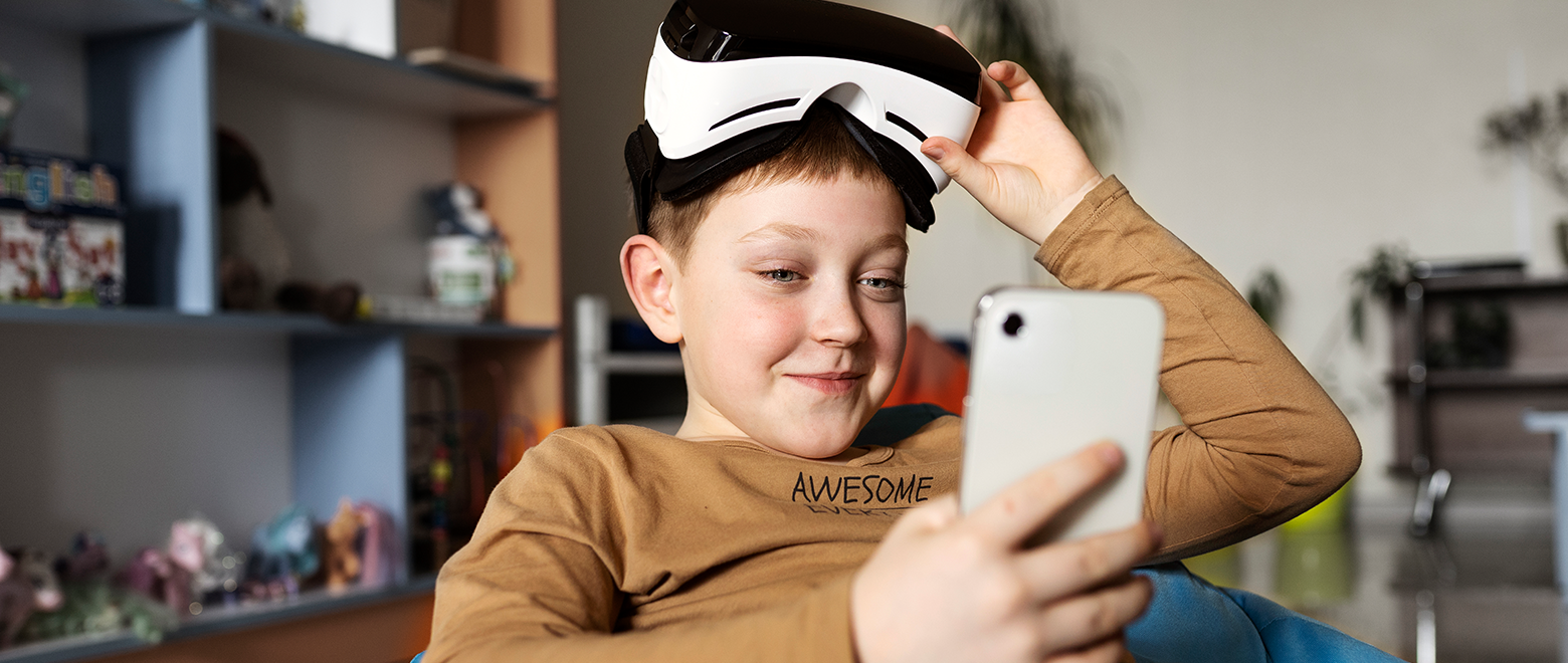Criança mexendo em um celular com um óculos de realidade virtual na cabeça.