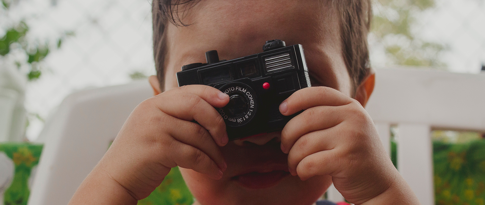 Criança segurando uma câmera em seu rosto