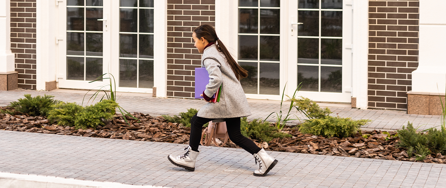 Menina voltando para escola com um caderno em sua mão